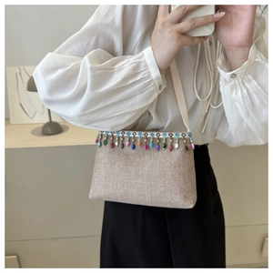 Détail du sac bandoulière tissé beige ethnique avec pompons en perles colorées
