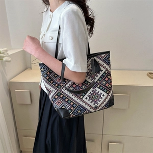 Ethnic woven tote bag with geometric patterns and black leather straps on a model