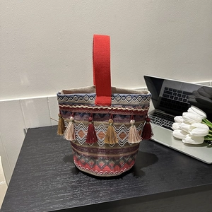 Dettaglio borsa etnica intrecciata con motivi geometrici colorati e nappe con frange