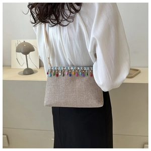 Détail d'un sac bandoulière en paille tressée avec des glands perlés et de la broderie