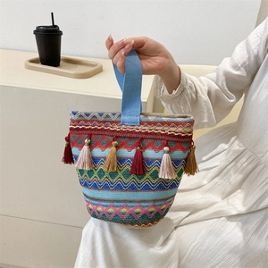 Dettaglio borsa boho in tessuto con motivi a onde colorate e ciondoli con nappe decorative