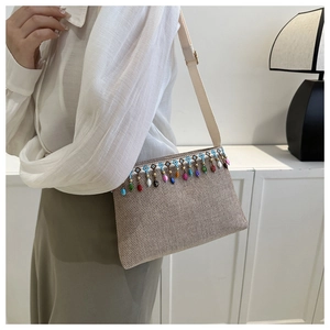 Détail d'un sac bandoulière tissé beige bohème avec perles colorées et pompons