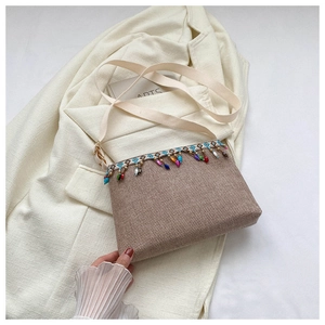 Gros plan d'un sac bandoulière tissé kaki avec perles colorées et pompons à franges