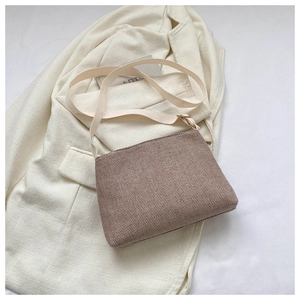 Détail de la texture d'un petit sac tissé rose poudré sur un blazer blanc élégant
