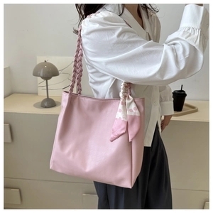 Pink tote bag detail with hand-woven handle and decorative silk scarf on pink faux leather