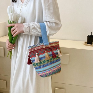 Dettaglio della borsa tessuta boho con motivi geometrici colorati e nappe pendenti