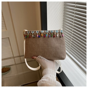 Détail du sac bandoulière tissé bohème avec pompons en perles colorées et broderie ethnique