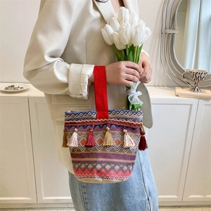 Dettaglio della borsa tote etnica con trame geometriche colorate e nappe decorative