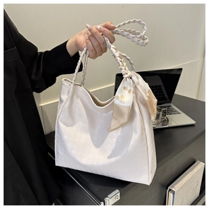 Detail of cream woven tote bag with texture, braided handle and elegant silk scarf
