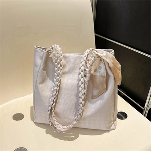Detail of beige houndstooth tote bag with woven handles and decorative silk scarf