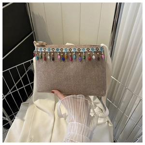 Détail du sac tissé bohème avec glands de perles colorés et broderie géométrique