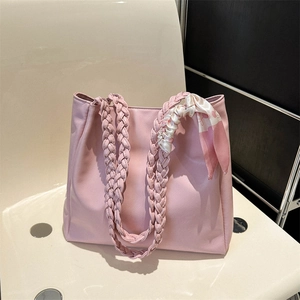 Detailed view of a pink woven handle tote bag decorated with a stylish floral silk scarf