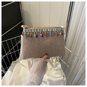 Détail du sac bandoulière tissé avec pompons de perles colorées et motif géométrique