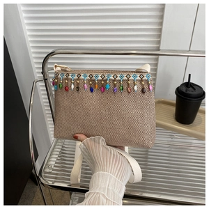 Détail d'un sac bandoulière tissé beige avec des perles ethniques et broderies géométriques