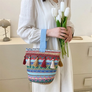 Dettaglio di borsa a secchiello bohémien tessuta con nappe e motivi geometrici