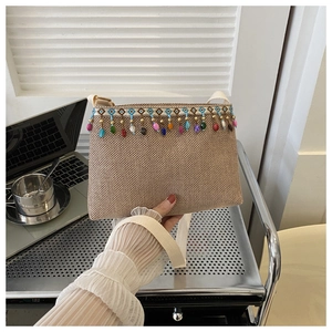 Détail d'un sac bandoulière tissé avec pompons de perles colorés et sangle en tissu