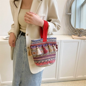 Dettaglio di borsa etnica intrecciata con strisce colorate e nappe in stile boho