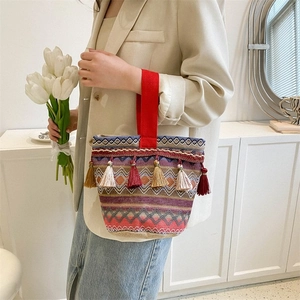 Dettaglio della borsa a mano boho tessuta con nappe colorate e texture geometrica