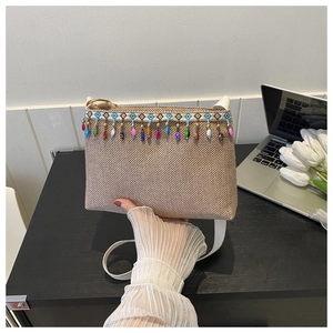 Détail d'un sac bandoulière tissé bohème avec des pompons en perles colorées et garniture bleue