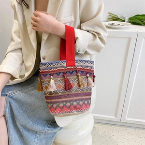 Dettaglio della borsa etnica intrecciata con tracolla rossa e ciondolo con nappe