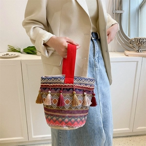 Dettaglio della borsa a secchiello etnica intrecciata con motivi geometrici e nappe colorate