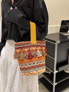 Dettaglio borsa a secchiello etnica con motivi geometrici colorati e nappe vivaci