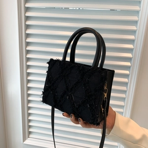 Chic black quilted handbag with distressed edges and detachable shoulder strap