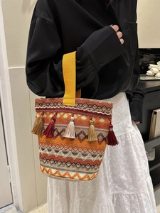 Dettaglio di borsa a secchiello boho colorata con motivi a onde e nappe multicolore