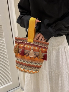Dettaglio del ricamo etnico colorato e delle frange boho sulla borsa a secchiello a mano