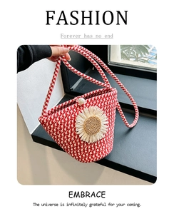 Détail d'un sac seau tressé rouge et blanc avec marguerite et fermoir en perle