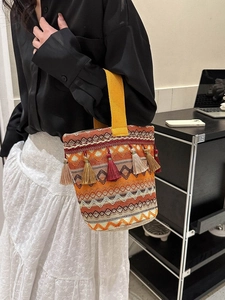 Dettaglio della borsa etnica intrecciata con nappe colorate e ampi manici gialli vivaci