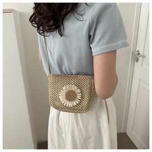 Detail of woven straw crossbody bag featuring large daisy floral decoration on the front