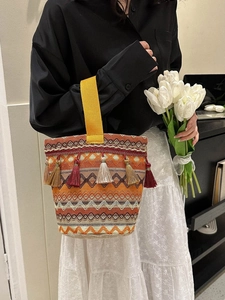 Dettaglio borsa a secchiello boho con motivi jacquard colorati e lunghe frange nappe