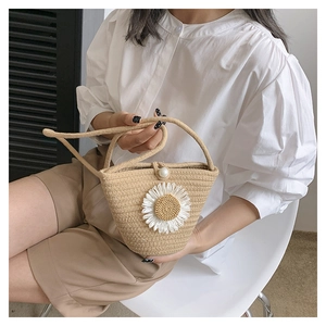 Vue détaillée d'un sac en paille tissé avec applique de marguerite et fermoir en perle