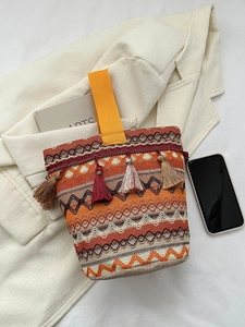 Dettaglio della borsa boho intrecciata con nappe colorate e motivi geometrici a onde