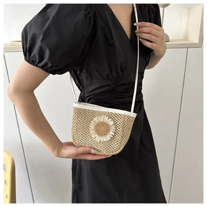 Detail van minimalistische stro-emmer tas met witte madelief en dunne lederen riem