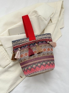 Dettaglio borsa a secchiello etnica intrecciata con frange colorate e manico rosso