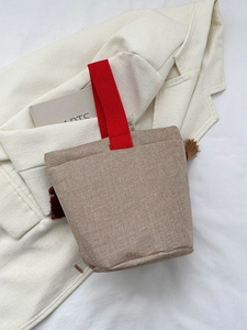Dettaglio dei manici in tessuto rosso e nappe decorative sulla borsa ricamata