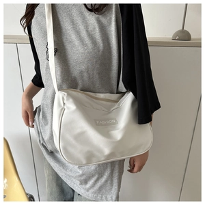 Dettaglio della borsa a tracolla in nylon bianco con patch fashion e zip sulla modella