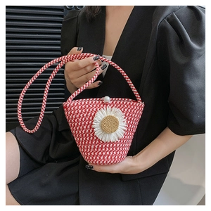 Détail du sac seau tissé rouge et blanc avec fleur de marguerite et fermoir perle