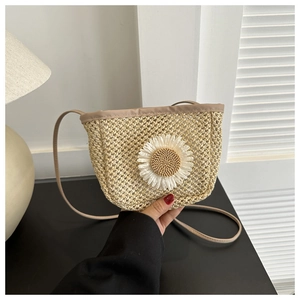 Detail of straw woven crossbody bucket bag with white daisy flower ornament
