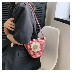 Détail d'un sac seau tissé rouge et blanc avec marguerite et fermoir perle