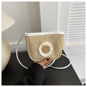 Detail of hand-woven straw bucket bag with white leather trim and daisy flower decoration