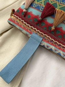 Dettaglio ravvicinato di borsa etnica ricamata con nappe colorate e motivi geometrici