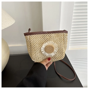 Detail of hand-woven straw bucket bag with large white daisy and brown leather strap
