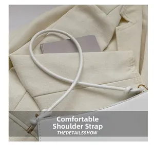 Détail du sac à bandoulière en cuir blanc avec fines bretelles et finitions en métal doré