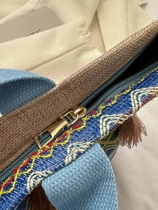 Dettaglio della borsa etnica intrecciata con onde geometriche, frange e zip dorata
