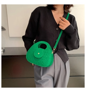 Détail du mini sac selle vert émeraude à texture crocodile avec boucle dorée sur modèle
