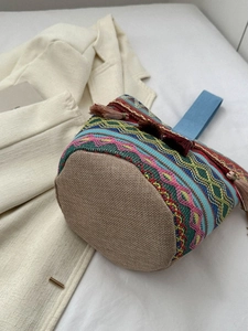 Dettaglio della borsa a secchiello a righe geometriche colorate con nappe e trama