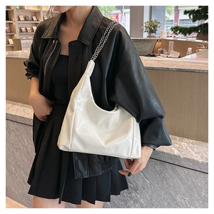 Détail du sac cabas en cuir verni blanc avec une élégante bandoulière en chaîne argentée